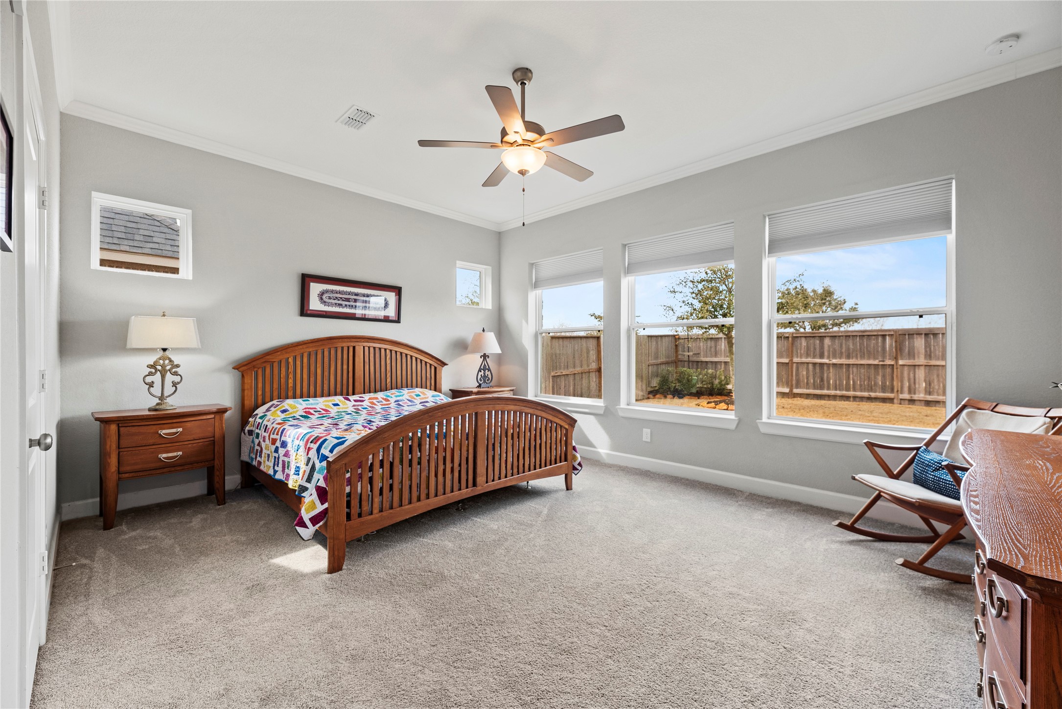3127 Swift Way Katy, TX 77493 - Photo 17 of 25 Primary retreat offers plush carpet, crown molding, ceiling fan, en-suite bathroom and backyard views.