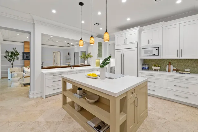 a kitchen that has a lot of white cabinets and stainless steel appliances