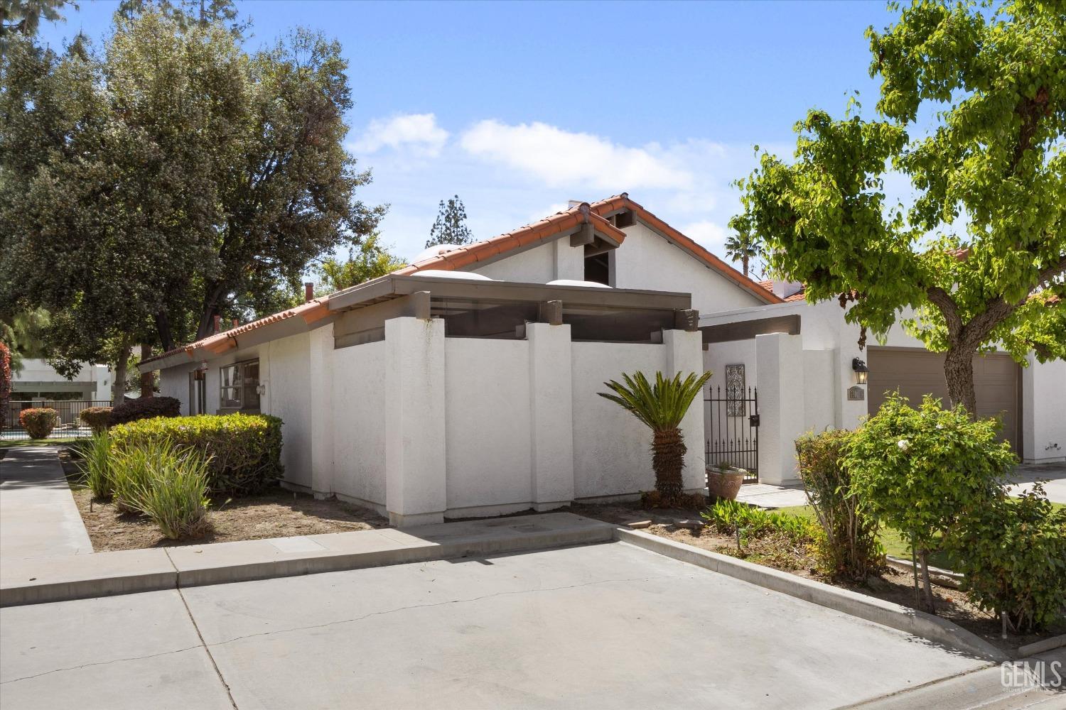 Undisclosed Address Bakersfield, CA 93309 - Photo 7 of 35 a view of a white house with a small yard and a large tree