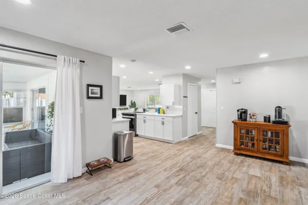 a large white kitchen with wooden floor and a sink