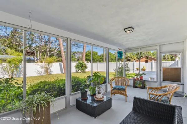 a living room with patio furniture and a floor to ceiling window