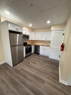 a kitchen with granite countertop a refrigerator and a stove top oven