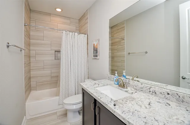 a bathroom with a granite countertop sink toilet and shower