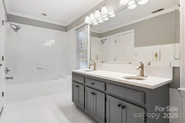 a bathroom with a sink double vanity granite tub shower and a mirror