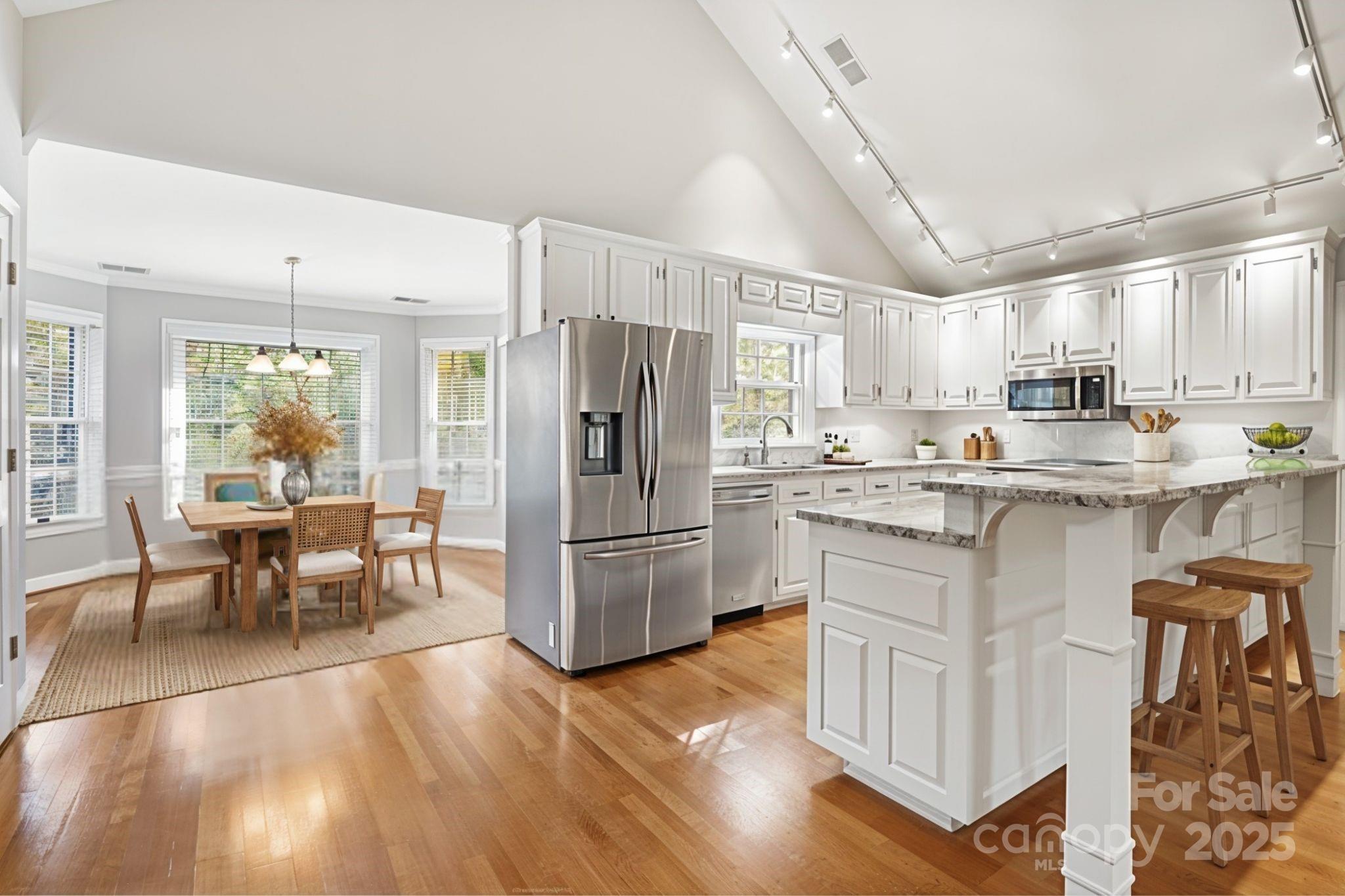 3475 Pikeview Road Fort Mill, SC 29715 - Photo 7 of 48 a kitchen with stainless steel appliances granite countertop a refrigerator a stove a sink a dining table and chairs with wooden floor