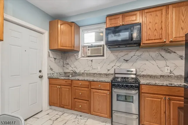 a kitchen with granite countertop stainless steel appliances a stove sink and microwave