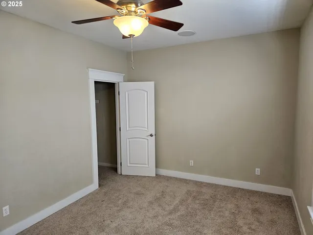 an empty room with a chandelier fan and a ceiling fan