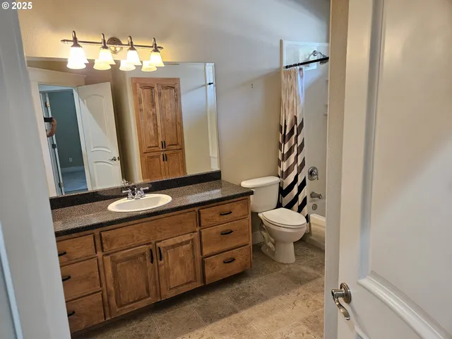 a bathroom with a granite countertop sink toilet and mirror