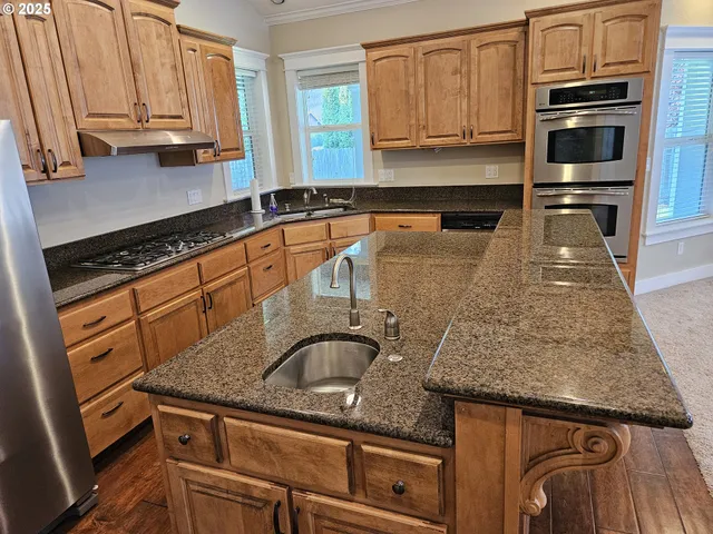 a kitchen with granite countertop a sink a stove and cabinets