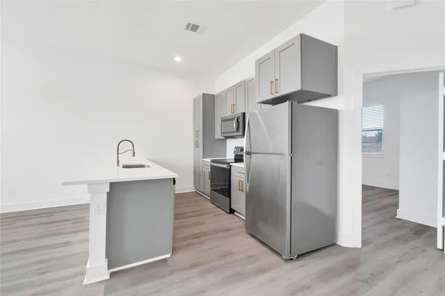 an empty room with wooden floor ceiling fan and windows