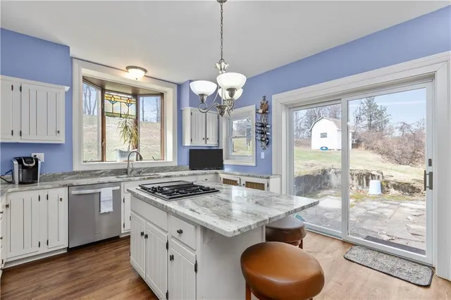 a kitchen with granite countertop a stove a sink a refrigerator and wooden floor