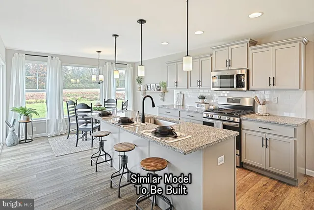 a kitchen with stainless steel appliances granite countertop a stove a sink a microwave a dining table and chairs with wooden floor