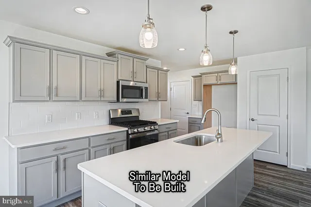 a kitchen with kitchen island a sink a stove a microwave and wooden floors