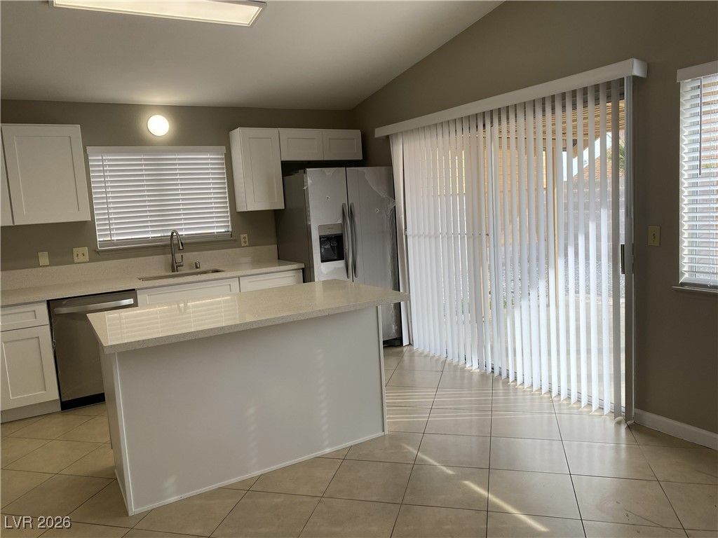 Undisclosed Address Las Vegas, NV 89108 - Photo 19 of 26 Kitchen with white cabinets, vaulted ceiling, stainless steel appliances, light tile patterned floors, and a center island