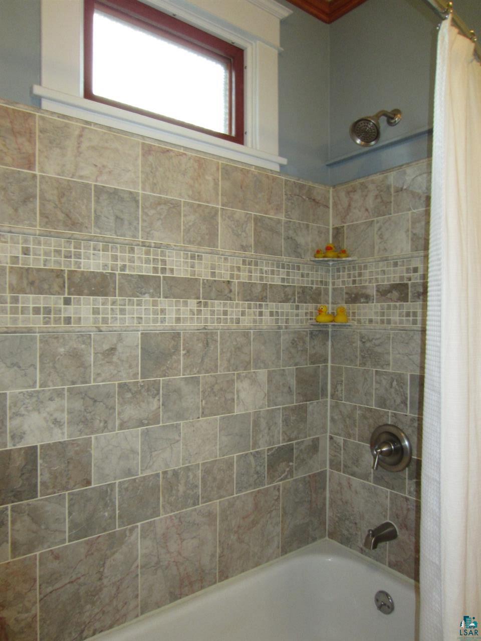 5137 London Road Duluth, MN 55804 - Photo 15 of 20 features vanity with granite counter top and marble tub surround.