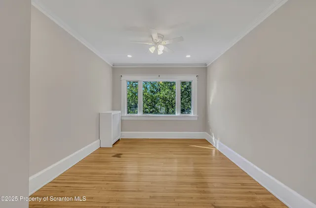 a view of empty room with wooden floor and fan
