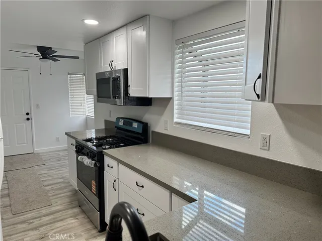 a kitchen with granite countertop a sink a stove and cabinets