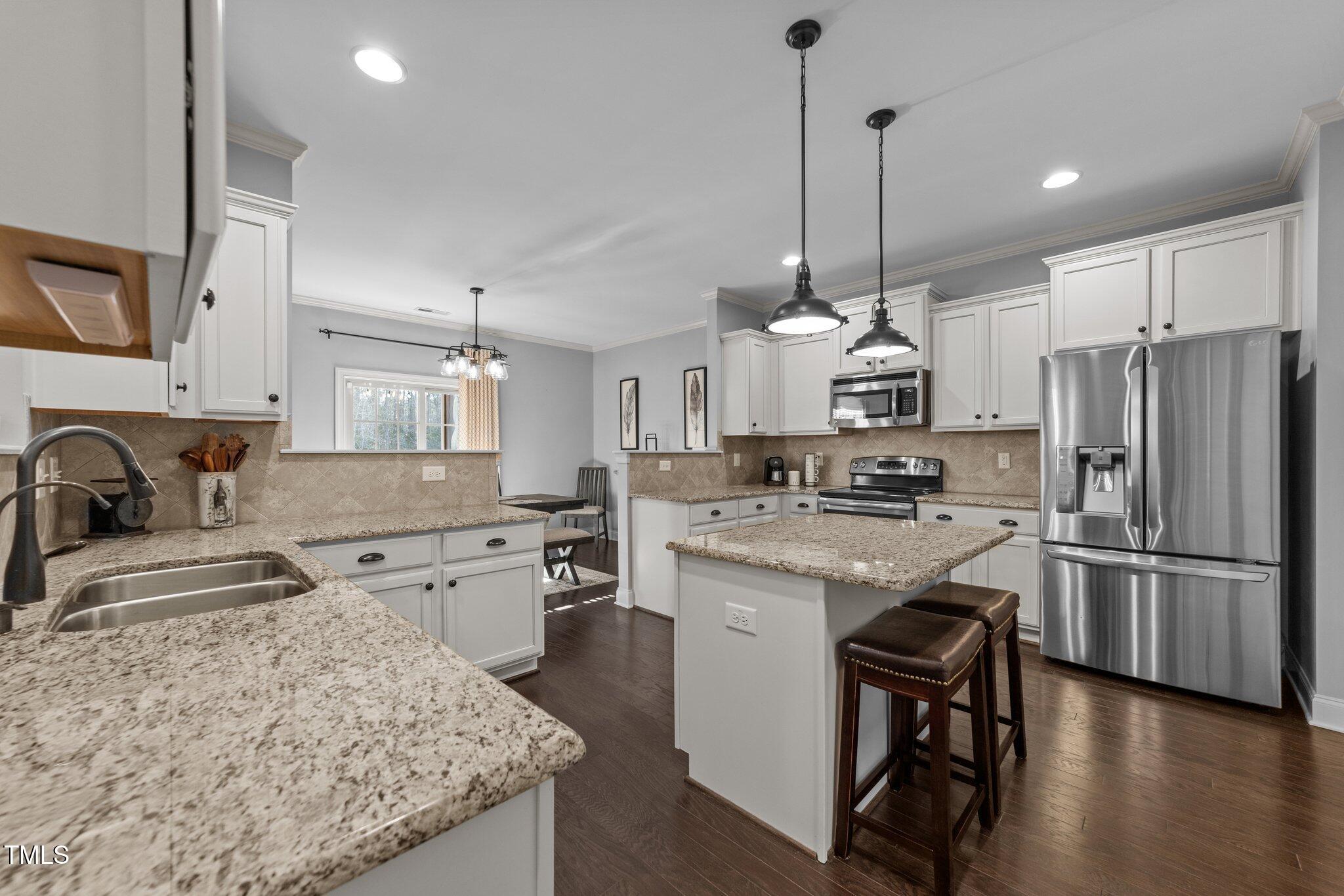 7520 Channery Way Raleigh, NC 27616 - Photo 16 of 47 a kitchen with stainless steel appliances granite countertop a stove refrigerator a sink dishwasher a oven with white cabinets and wooden floor