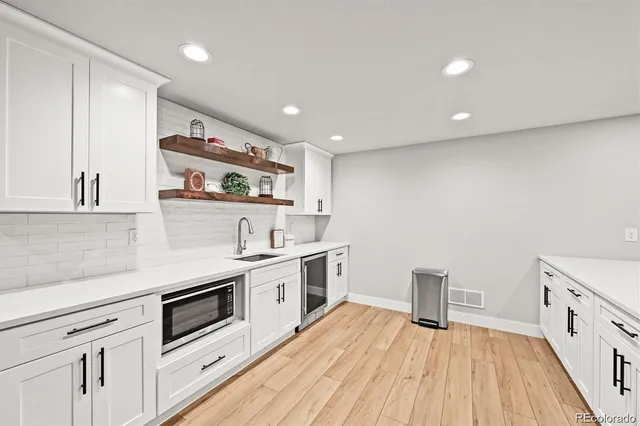 a kitchen with white cabinets stainless steel appliances and wooden floor