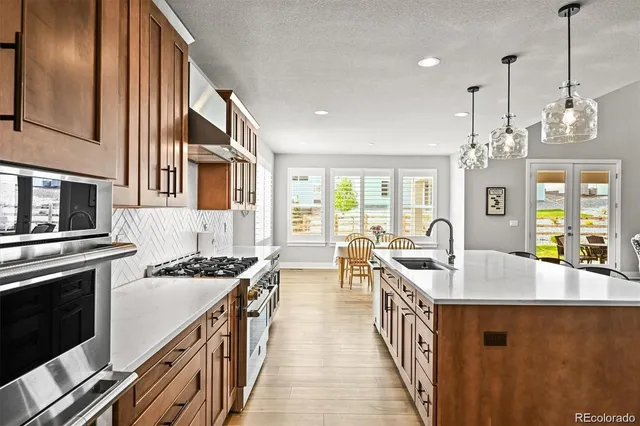 a kitchen with stainless steel appliances granite countertop a stove a sink dishwasher and a refrigerator with wooden floor