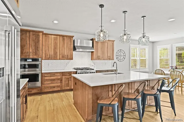 a kitchen with stainless steel appliances granite countertop a stove a refrigerator and a wooden floors