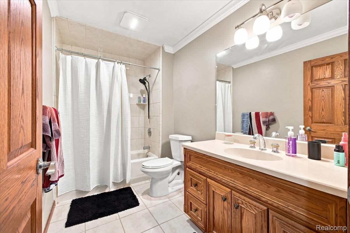 8610 Ferry Road Grosse Ile, MI 48138 - Photo 41 of 55 Bathroom featuring a wood-finish vanity with a light-toned countertop, a built-in sink, and a wall-mounted mirror