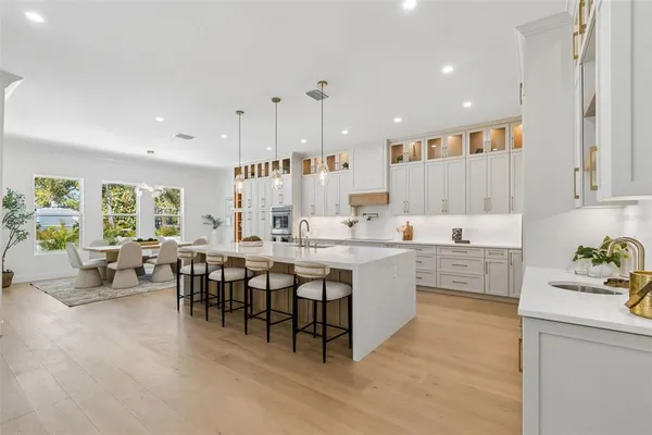 a kitchen with stainless steel appliances kitchen island granite countertop a dining table chairs and white cabinets