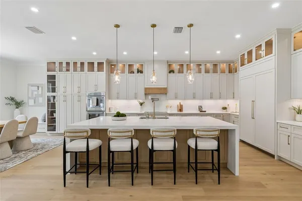 a kitchen with a sink a stove a refrigerator and white cabinets with wooden floor