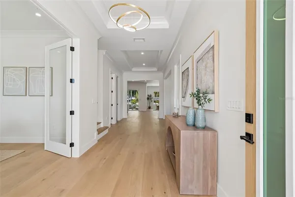 a view of a hallway with wooden floor windows and chandelier