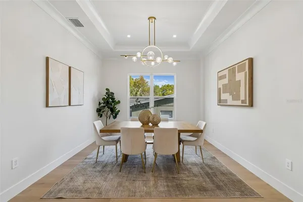 a dining room with wooden floor a chandelier a wooden table and chairs