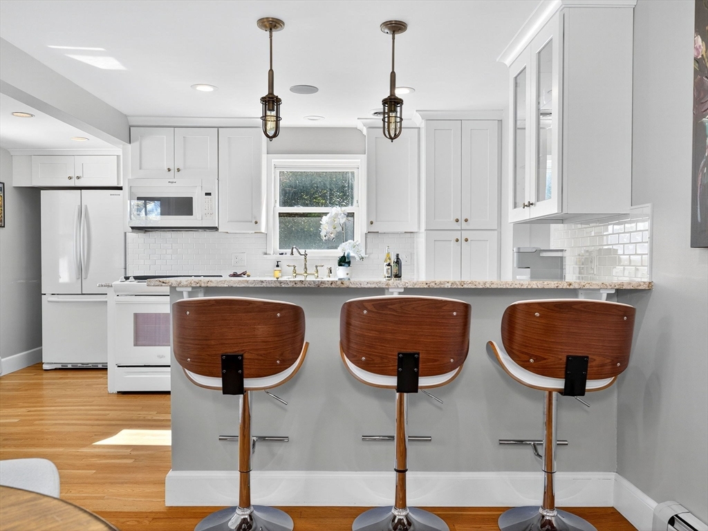 170 Payson Road Boston, MA 02467 - Photo 10 of 20 a very nice looking kitchen with granite countertop a stove a sink a kitchen island with white cabinets and wooden floor