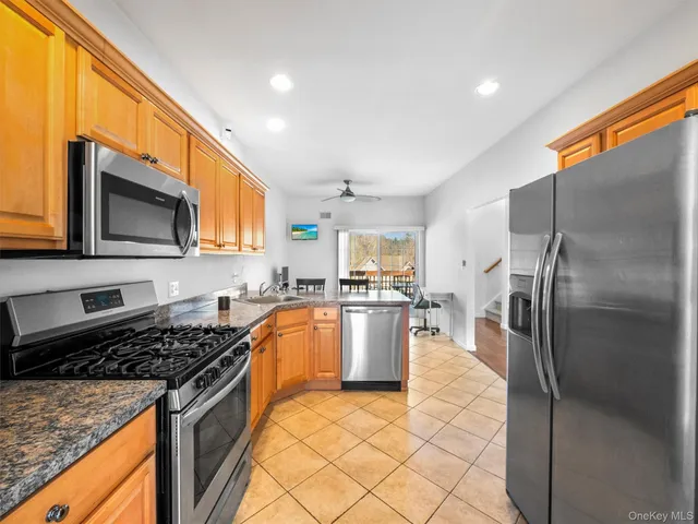 a kitchen with stainless steel appliances granite countertop a stove top oven a sink dishwasher a refrigerator and a microwave