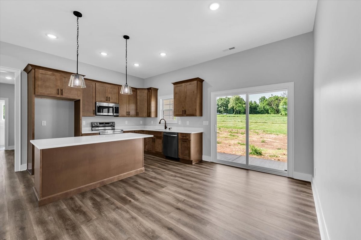 749 Edd Ramsey Road McMinnville, TN 37110 - Photo 10 of 40 a large kitchen with stainless steel appliances a large counter top a stove a sink dishwasher a refrigerator and a dining table with wooden floor