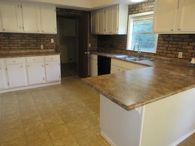 a kitchen with granite countertop a sink a stove and cabinets