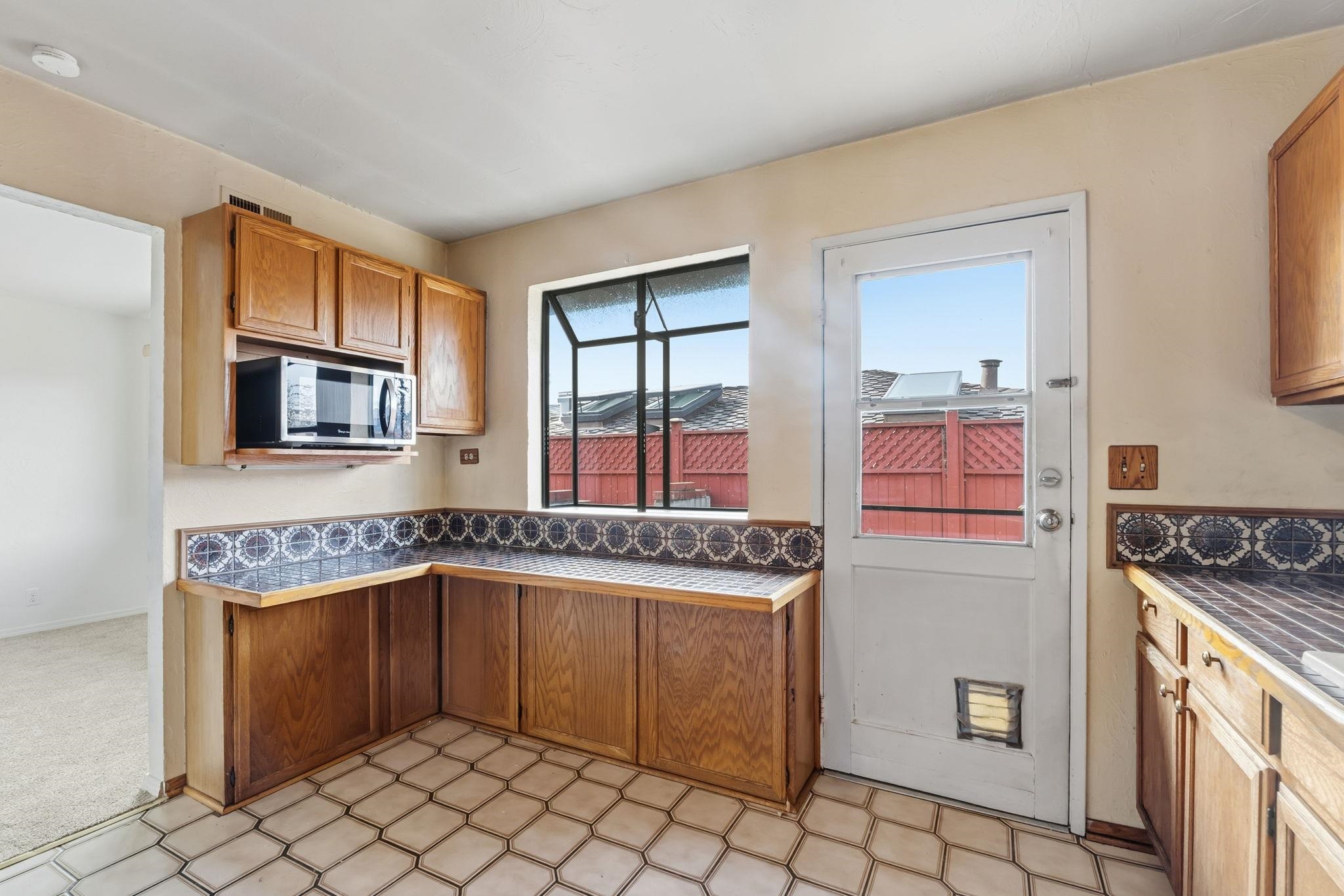 1609 Darwin Street Seaside, CA 93955 - Photo 11 of 26 Kitchen with light flooring, tile counters, stainless steel microwave, and wood finish cabinetry
