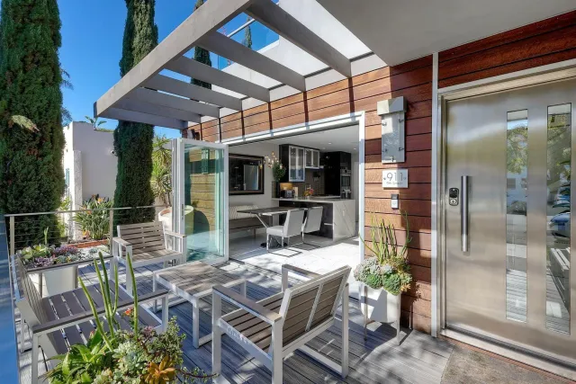 a view of a patio with table and chairs potted plants and floor to ceiling window