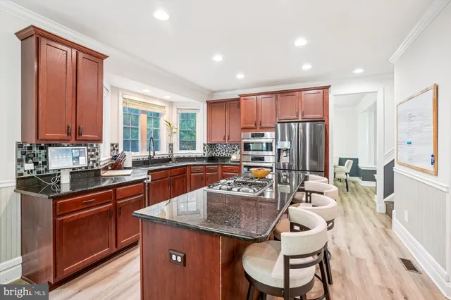 a kitchen with stainless steel appliances granite countertop a stove top oven a sink dishwasher a dining table and chairs with wooden floor