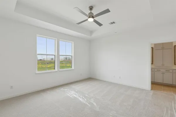 an empty room with chandelier fan and windows