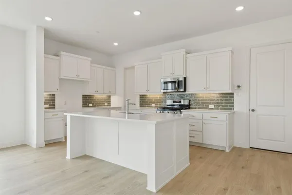 a kitchen with stainless steel appliances granite countertop a refrigerator sink and white cabinets