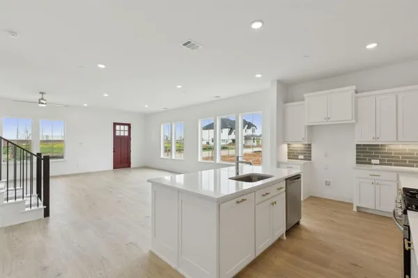 a large white kitchen with stainless steel appliances granite countertop a lot of counter space and wooden floor