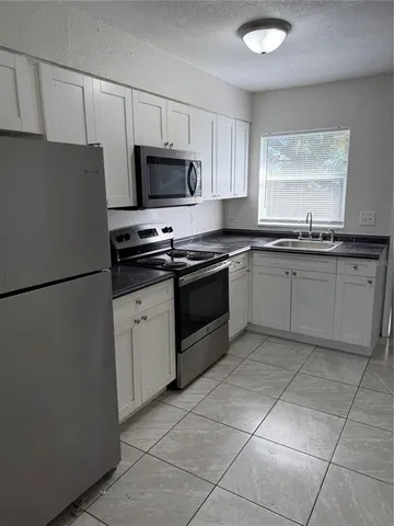 a kitchen with stainless steel appliances granite countertop a refrigerator sink and stove