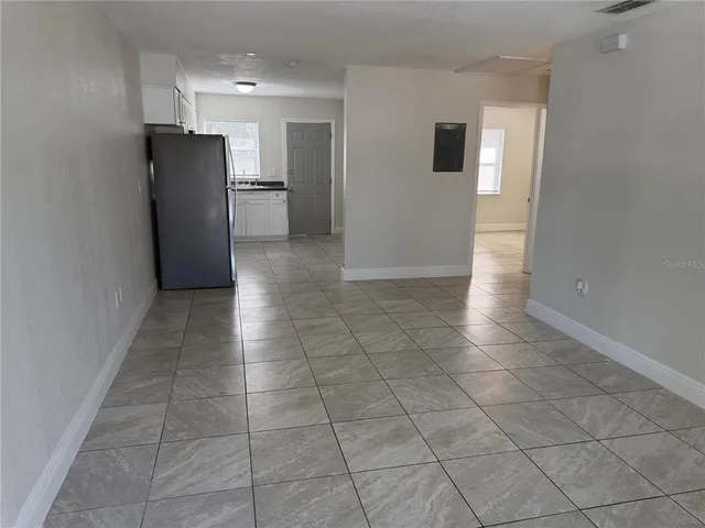 a view of a refrigerator in kitchen and an empty room