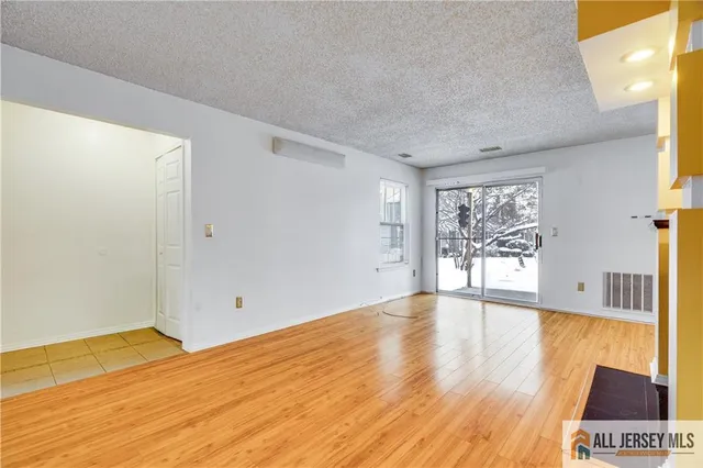 a view of an empty room with wooden floor and a fireplace