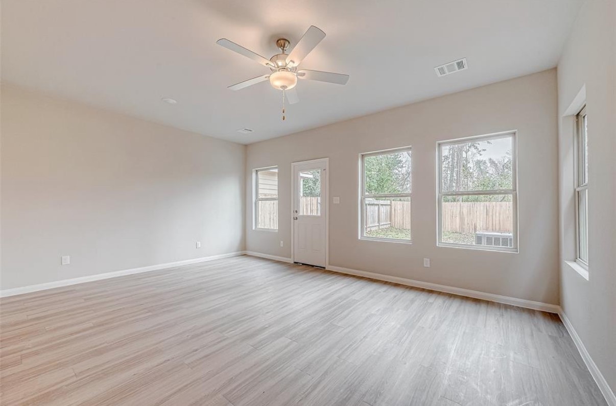 a view of an empty room with wooden floor and window
