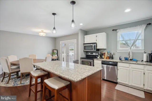 a kitchen with kitchen island white cabinets appliances and wooden floor
