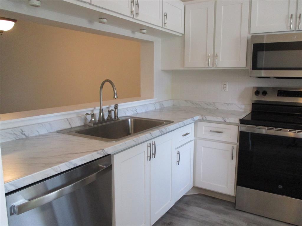 22040 Palms Way, Unit 205 Boca Raton, FL 33433 - Photo 7 of 19 a kitchen with white cabinets a sink and a stove with wooden floor