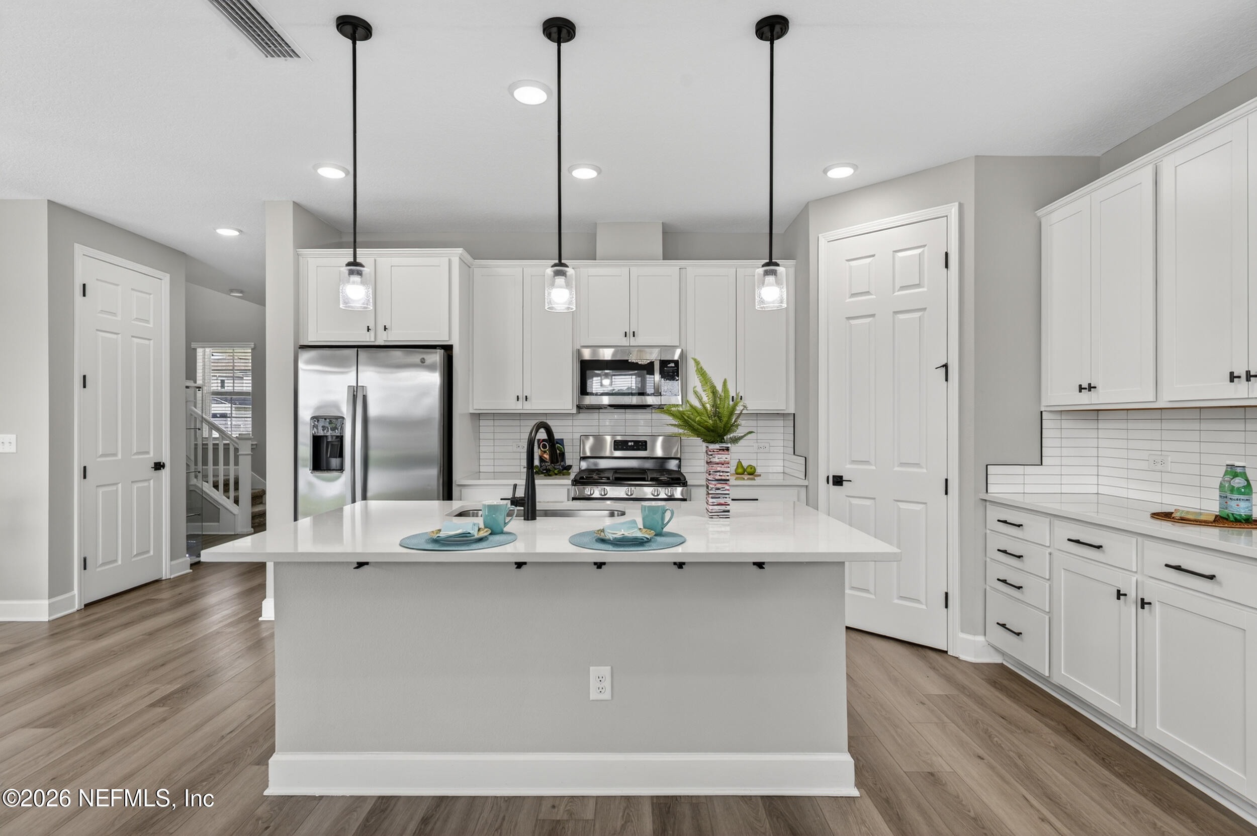 57 Cedar Elm Way St. Augustine, FL 32092 - Photo 12 of 65 a large kitchen with stainless steel appliances kitchen island granite countertop a stove a refrigerator a sink and white cabinets with wooden floor