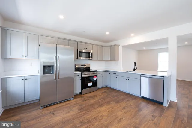 a kitchen with cabinets wooden floor and stainless steel appliances