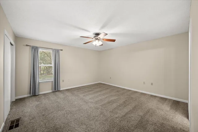 an empty room with fan and windows