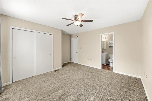 an empty room with closet and a ceiling fan